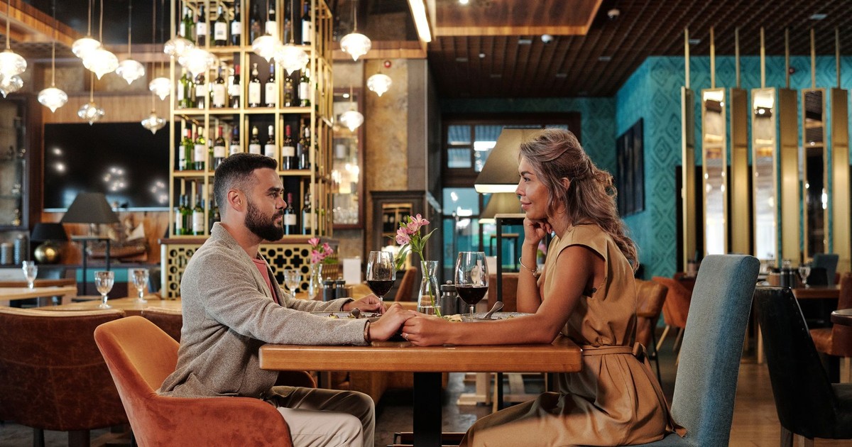 Couple enjoying a romantic dinner with wine in an elegant restaurant setting, creating a warm atmosphere.