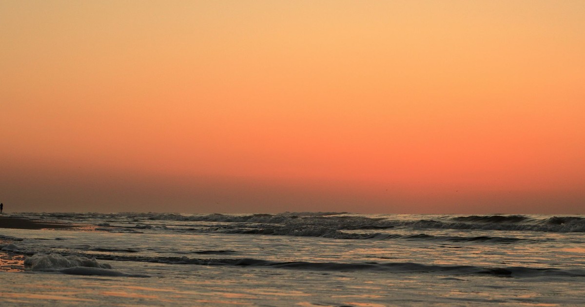 A tranquil sunset at Hilton Head Island with vibrant orange skies and gentle ocean waves.
