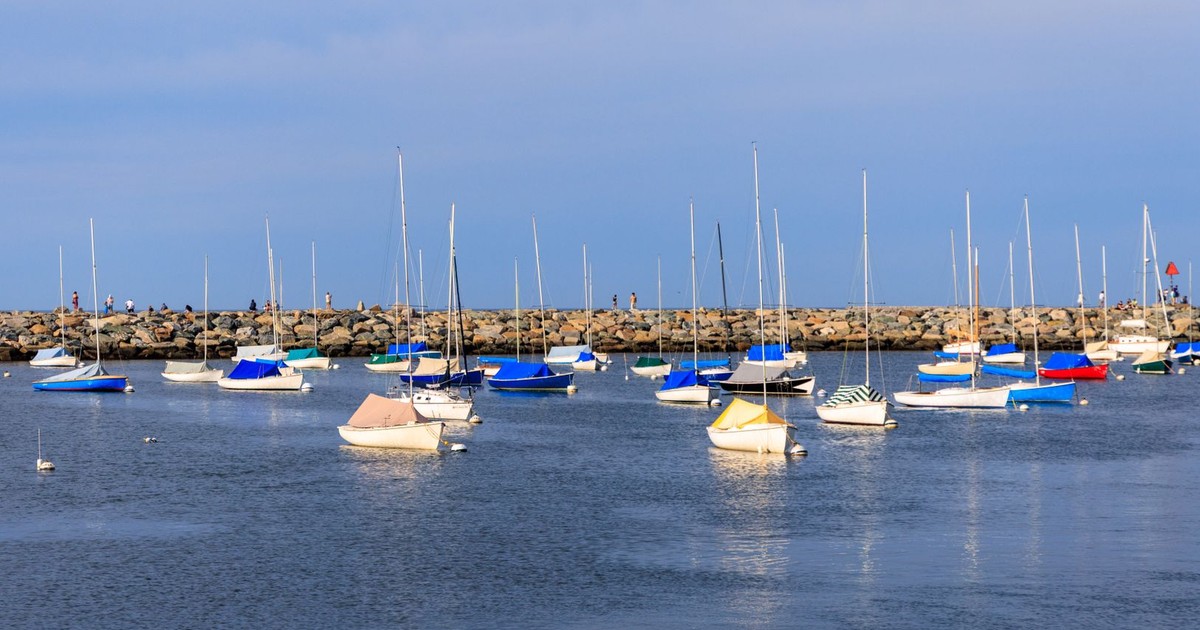 Colorful sailboats anchored in peaceful Rockport Harbor under a clear blue sky.