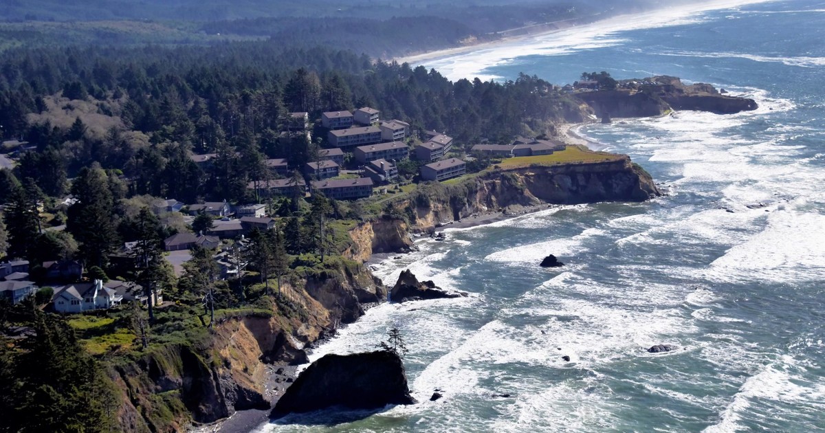 A stunning coastal view of a town perched on cliffs by the sea with waves crashing below.