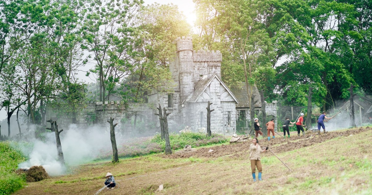 Farmers working in a field near a stone castle during a summer day, surrounded by greenery and smoke.