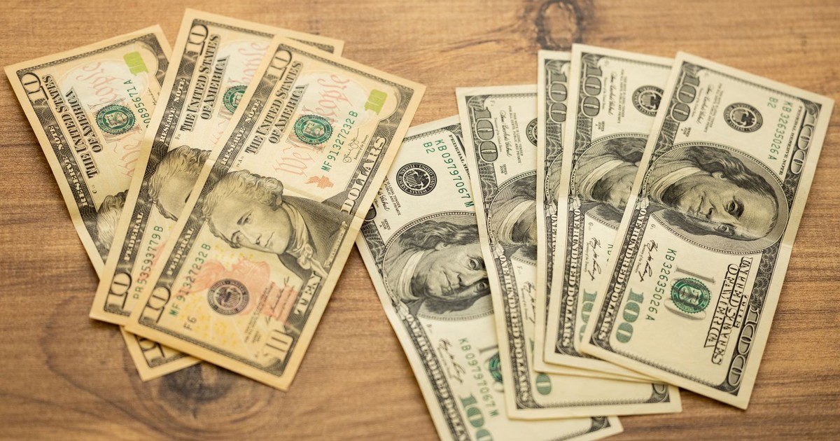 A collection of US dollar bills arranged on a wooden surface, showcasing currency denominations.