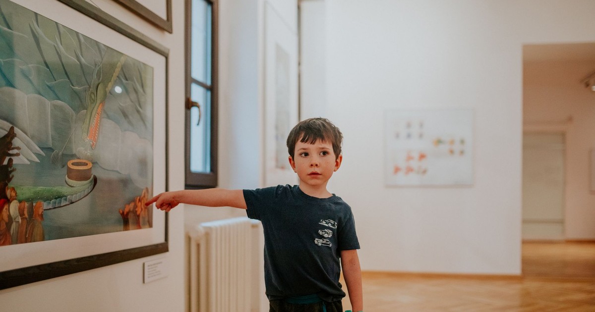 A young boy pointing at artwork in a modern art gallery, showing interest and curiosity.