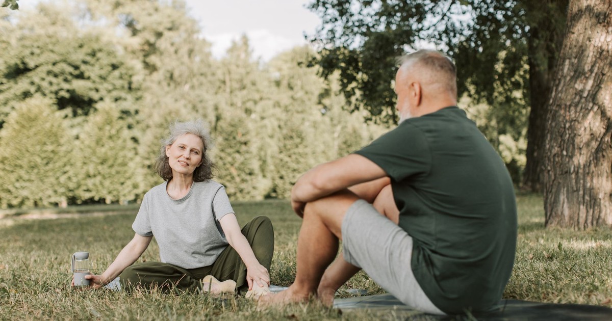 Senior couple practicing yoga and enjoying nature in a sunny park.
