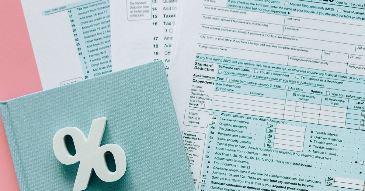 Tax documents with a percentage symbol on a pink and blue desk setup, emphasizing finance.