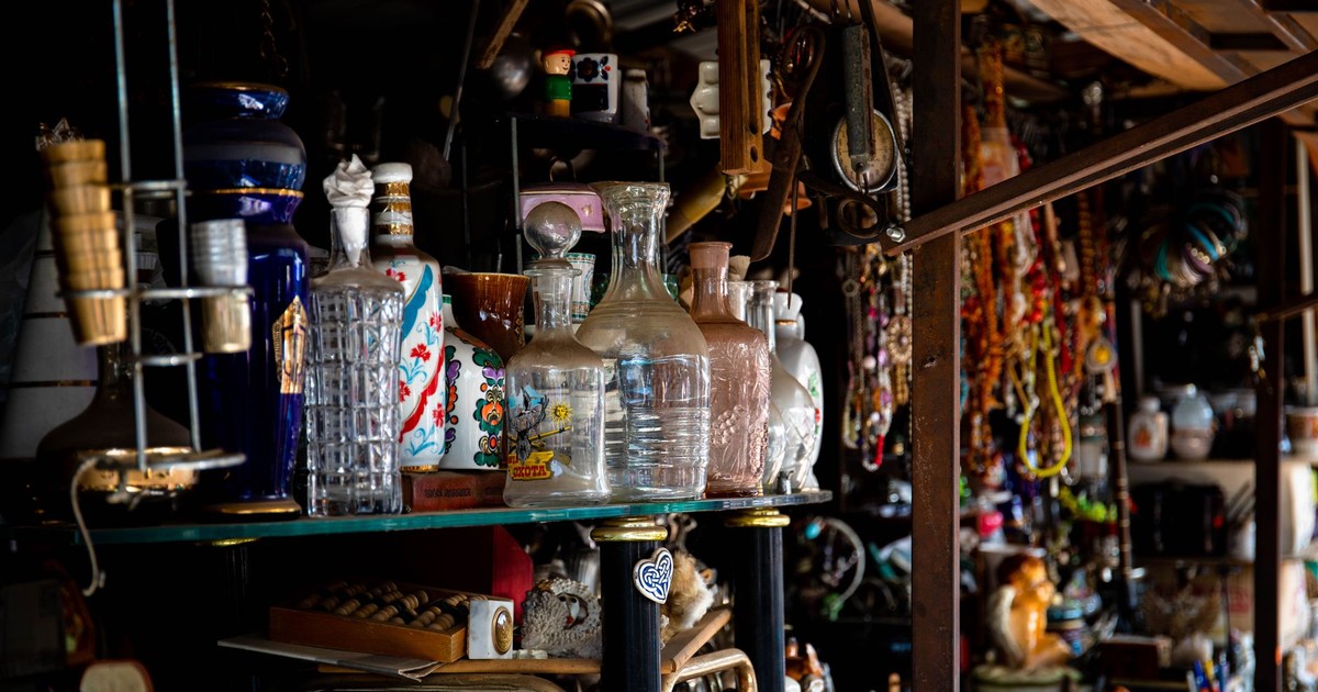 Eclectic assortment of vintage glassware and decor items displayed on a shelf in an antique store.