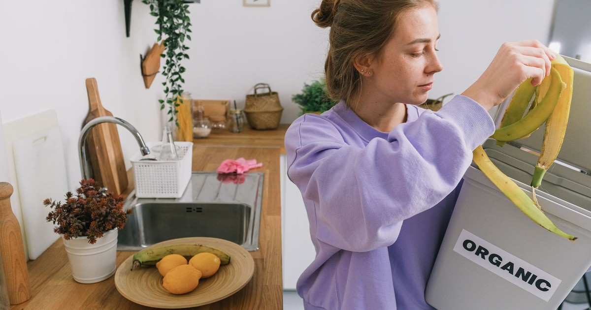 A woman composts banana peels in an indoor organic bin, promoting sustainable living.