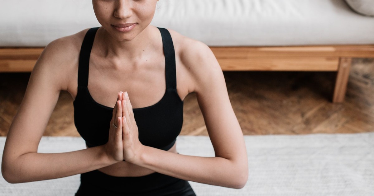 A woman in activewear meditating indoors, embodying peace and relaxation.