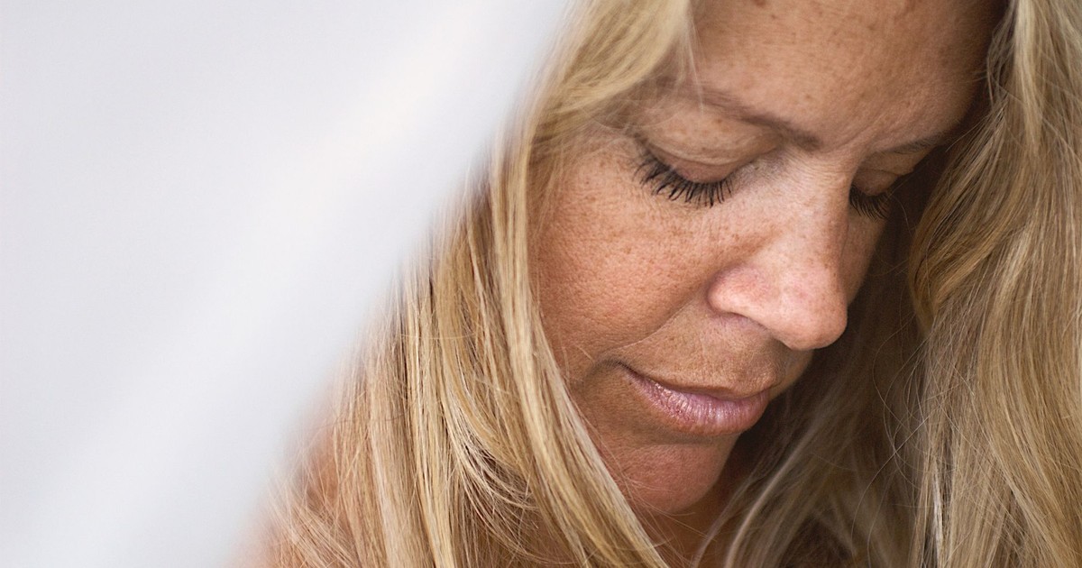 Close-up portrait capturing the serene expression of a blonde woman in a moment of quiet contemplation.