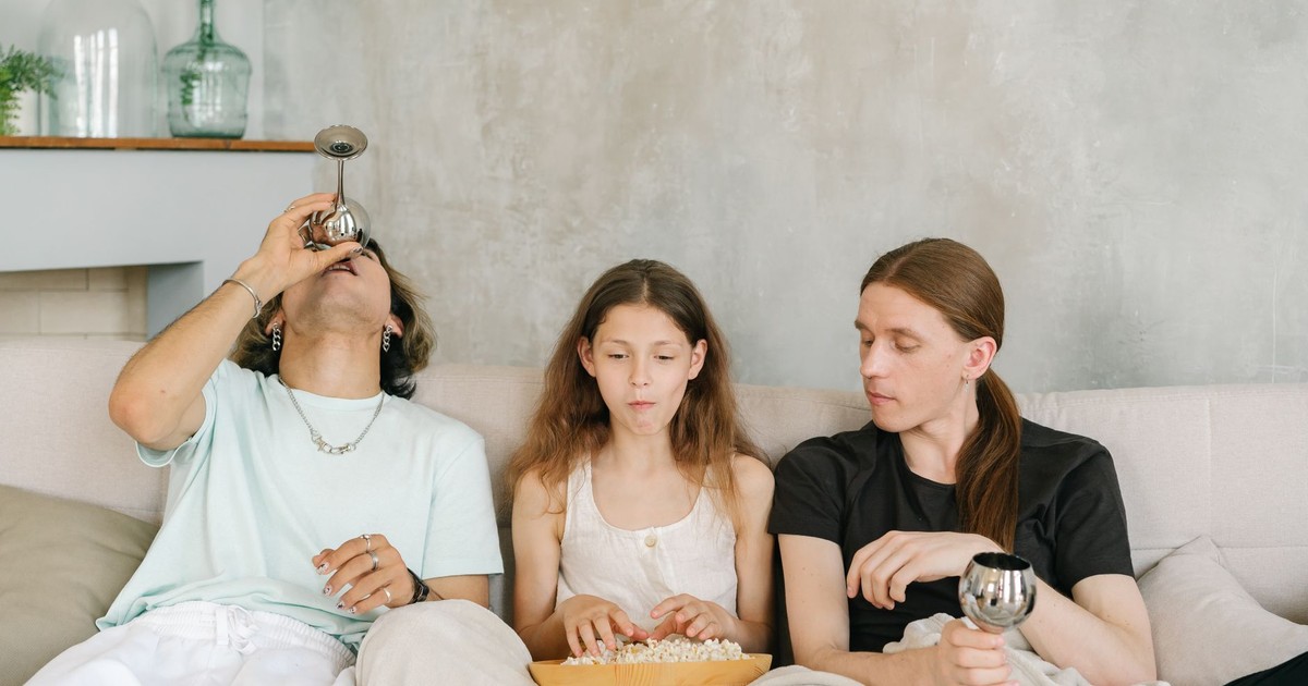 A diverse group of friends enjoying popcorn and drinks together on a cozy indoor sofa.