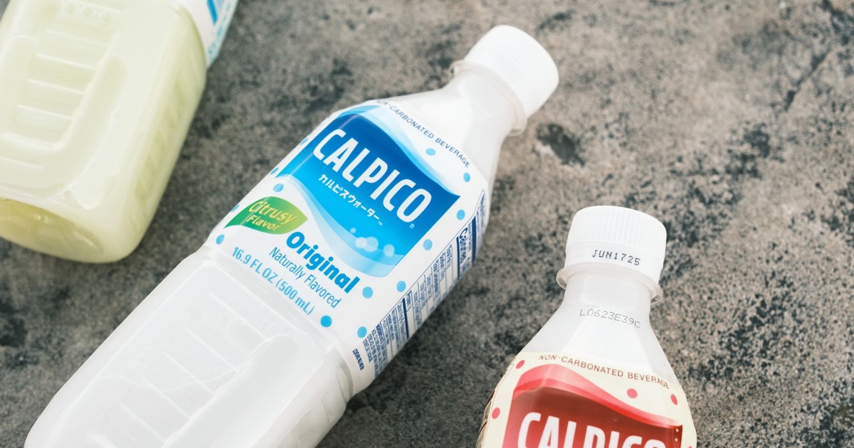 Close-up of Calpico beverage bottles on textured concrete surface.