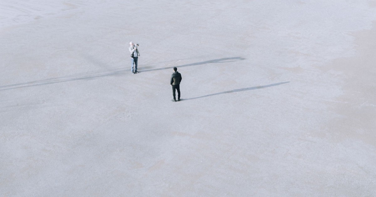 Two individuals on a vast, empty salt flat in İstanbul, Türkiye, casting long shadows in a minimalist landscape.