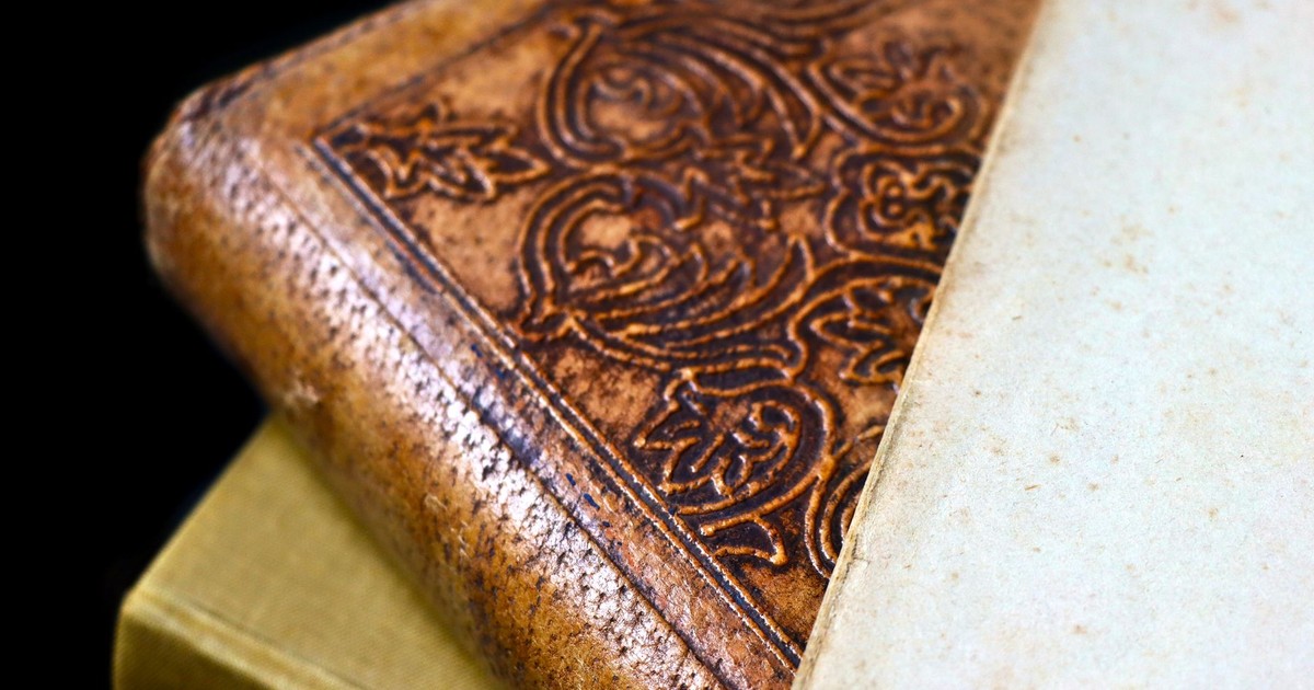 Detailed close-up of an antique leather bound book with ornate engraving and aged paper.