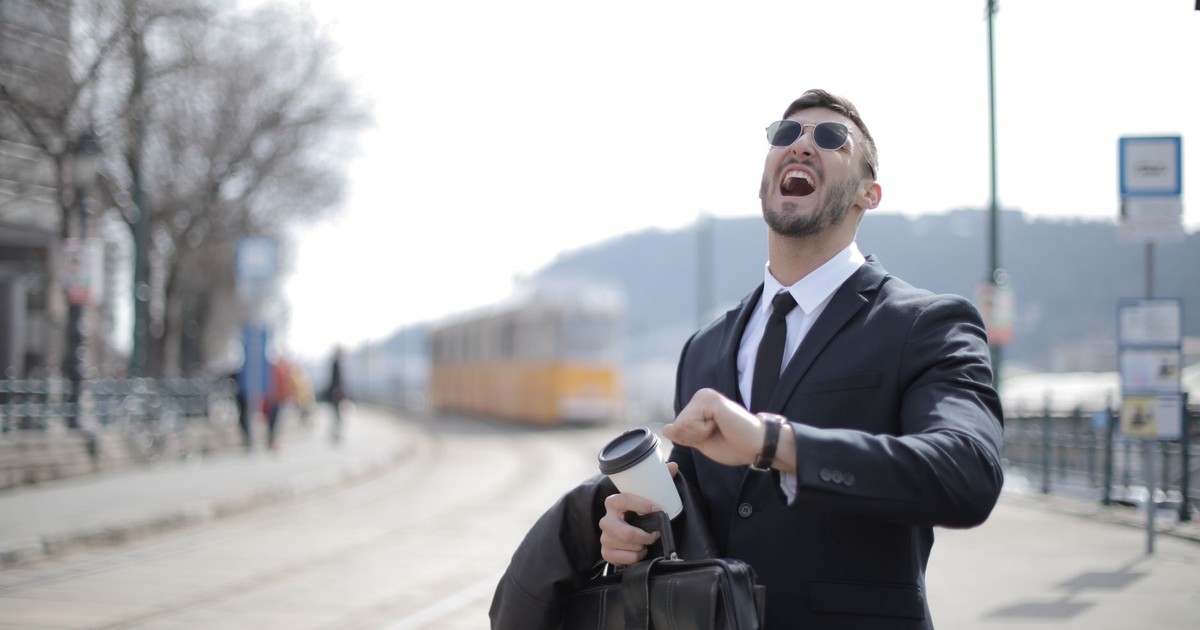 Businessman in sunglasses laughing while holding a coffee cup outdoors. Captures energy and expression.