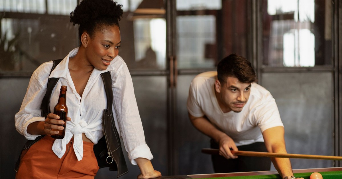 Young adults enjoying a casual billiards game in a modern bar. Perfect for leisure and lifestyle themes.