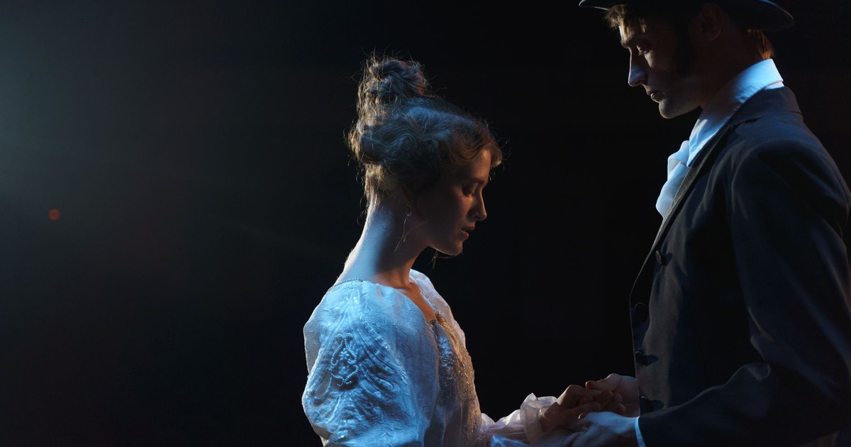 A dramatic scene depicting romance between two performers in period costumes on stage.