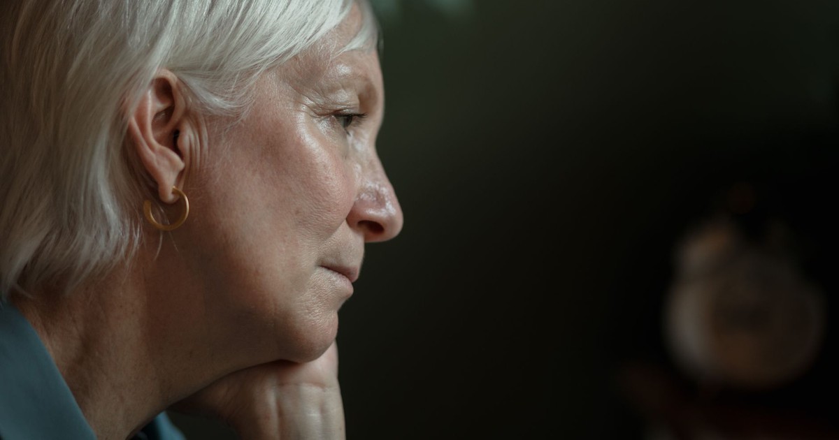 A thoughtful senior woman with white hair in a side profile view, lost in thought.