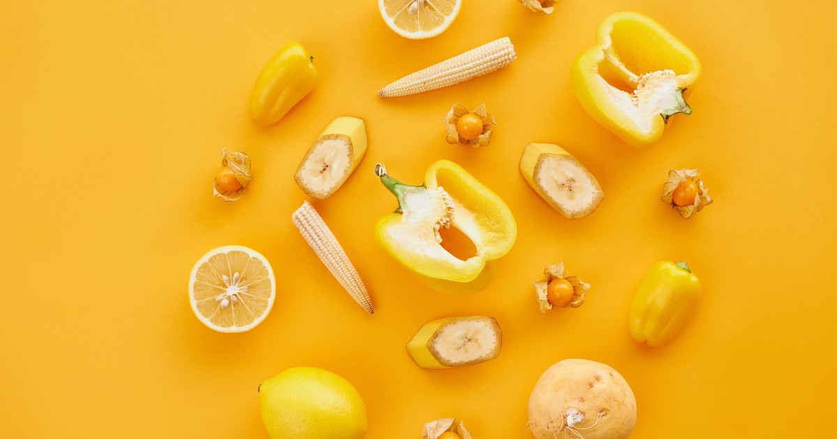 A colorful flat lay of yellow fruits and vegetables on a matching yellow background for a fresh and vibrant look.