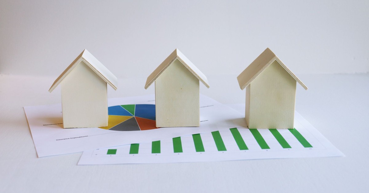 Wooden model houses on graphs depict real estate market analysis and trends.