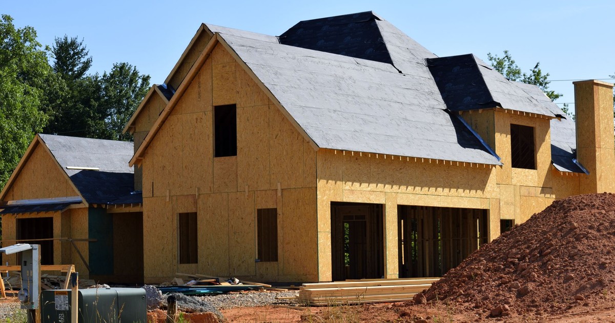 A partially built wooden house under construction, showcasing its progress and design in daylight.