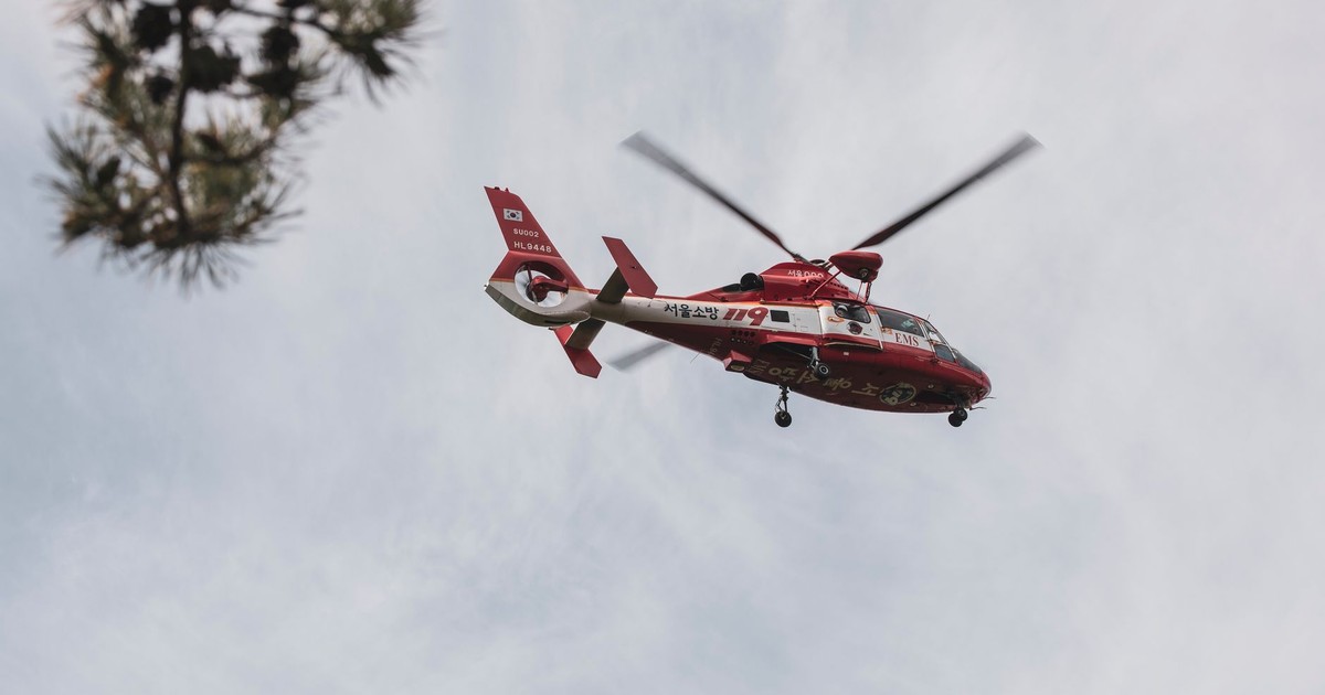 Red and white rescue helicopter flying in the sky, captured outdoors.