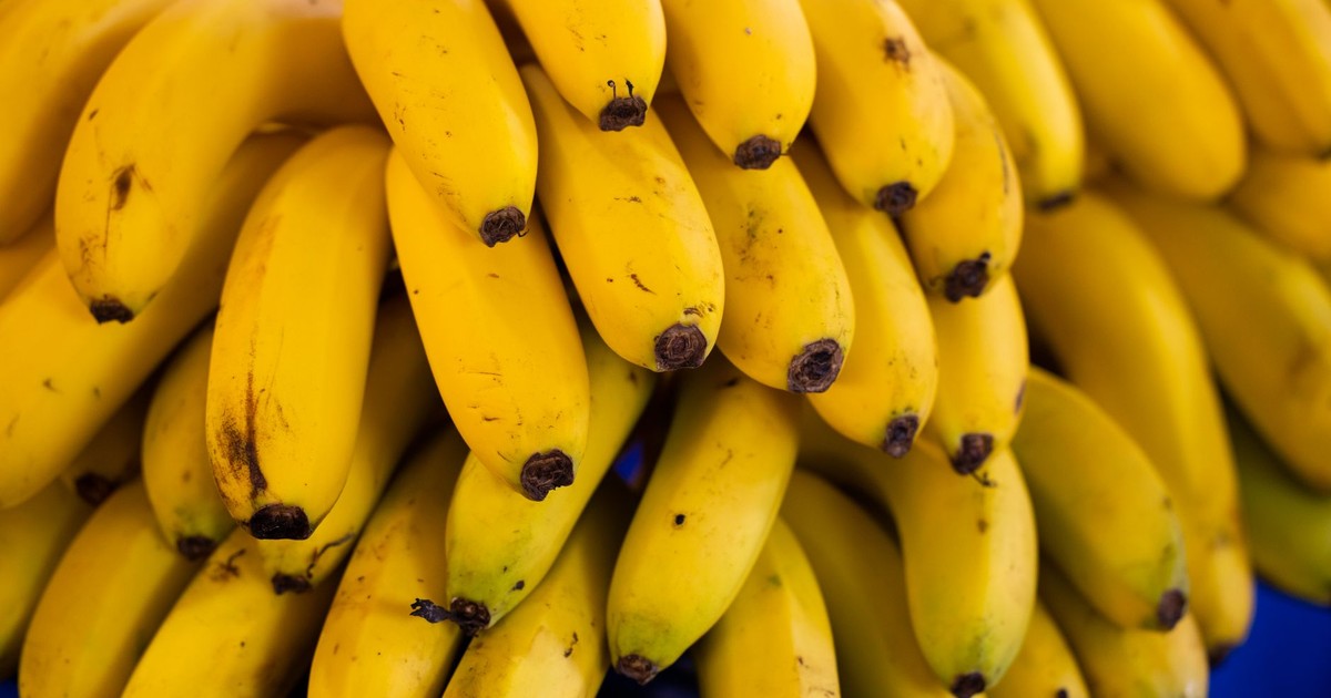 Cluster of bright yellow bananas stacked in a market, showcasing freshness and ripeness.