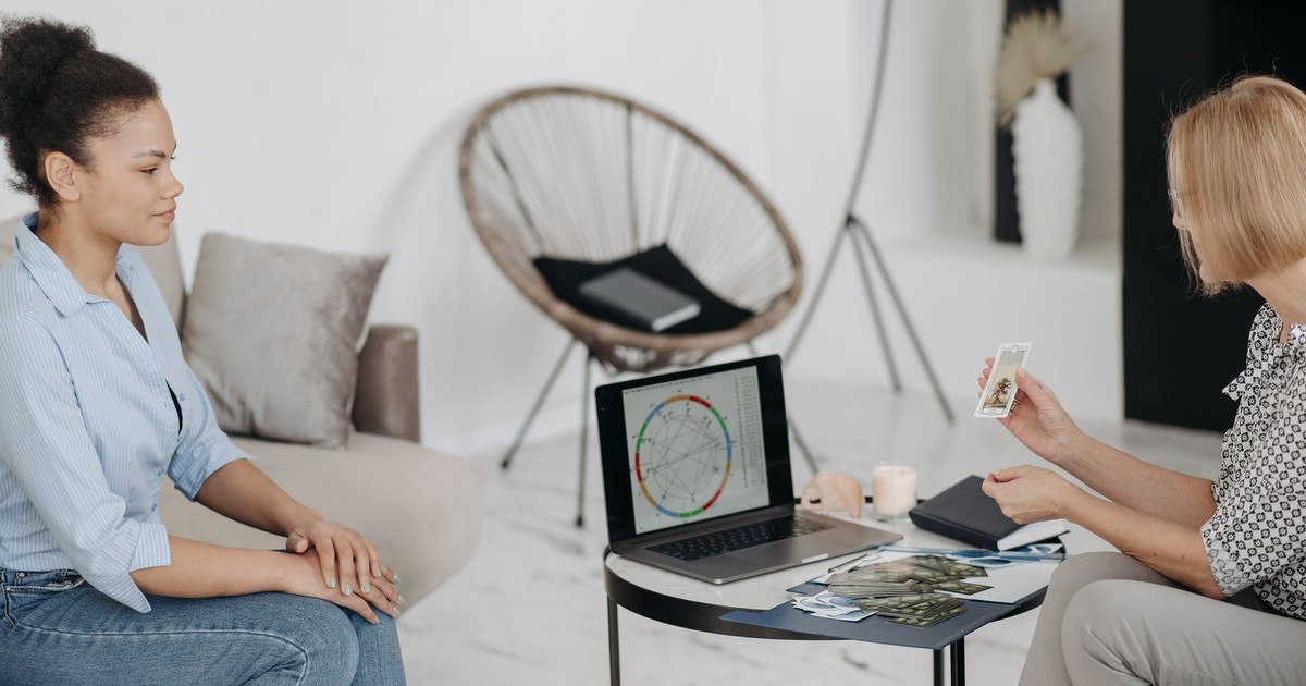 A tarot reader interprets cards and an astrological chart in a serene setting.