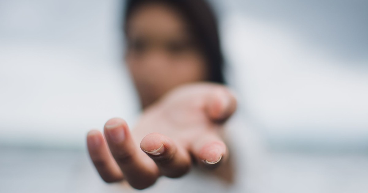 A soft focus image highlighting a reaching hand, symbolizing connection or help.