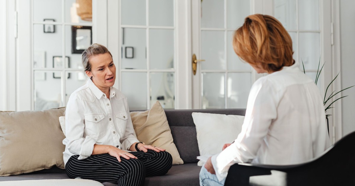 Two women having an intimate conversation on a sofa in a cozy indoor setting.