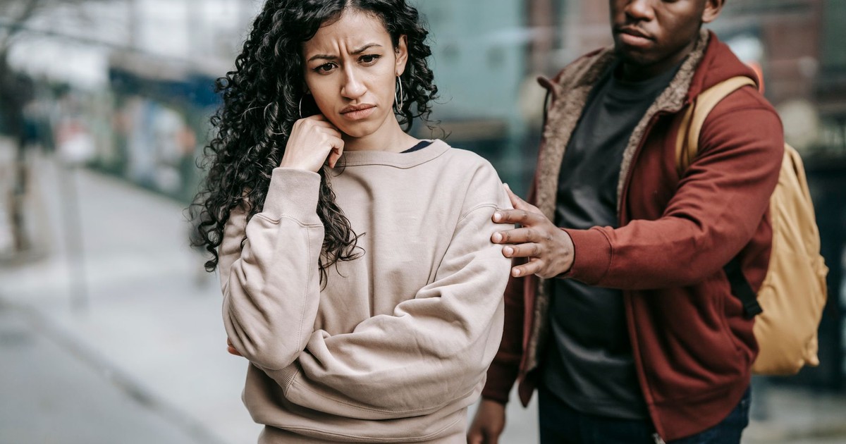 Sad young multiethnic couple in casual clothes standing in city street while having disagreement in daylight