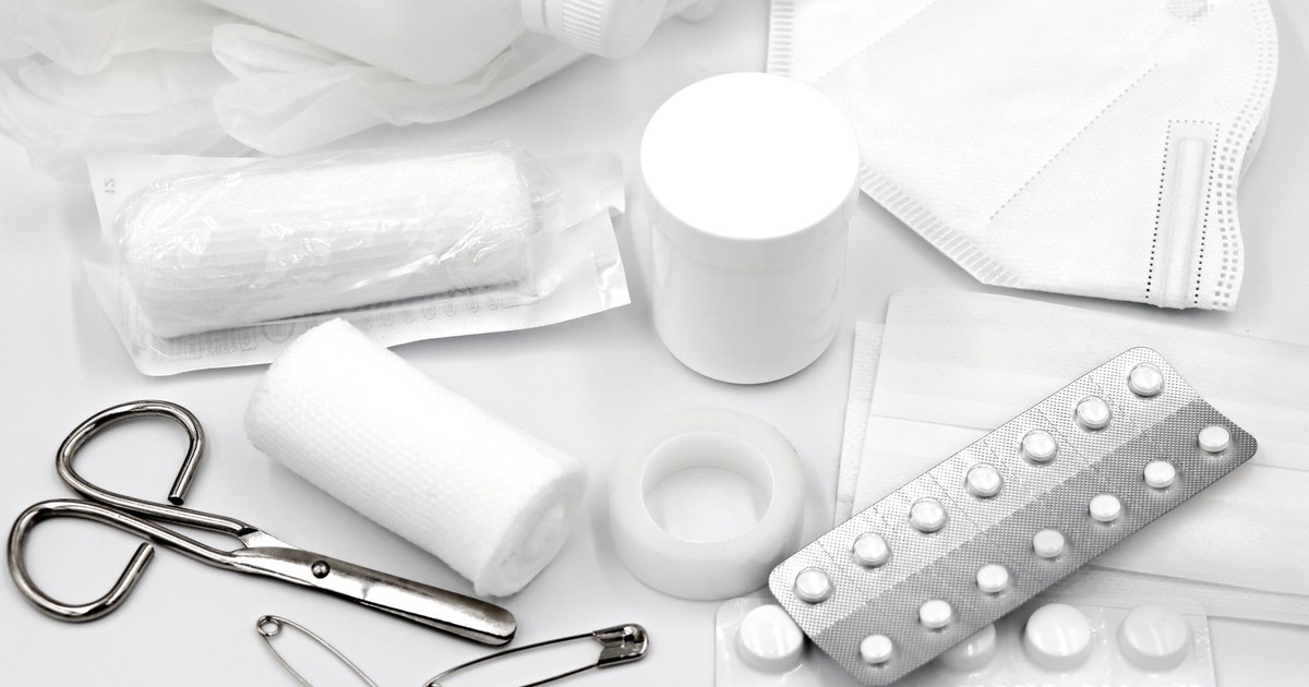 A flat lay of essential first aid supplies and medical equipment on a white background.