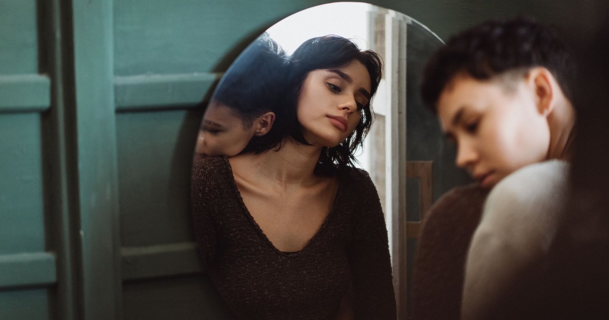Two people sharing a reflective moment, captured through a mirror in an intimate setting.