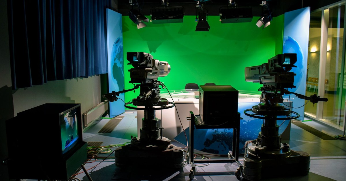 A TV studio setup featuring cameras and a green screen for production purposes.