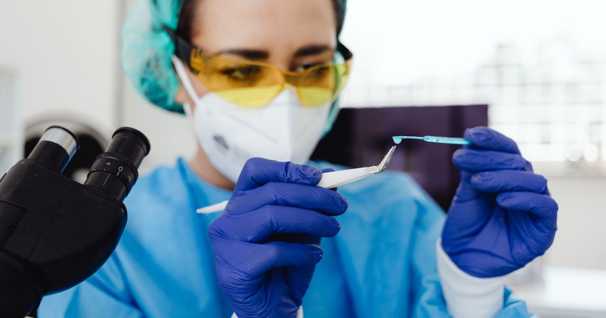 Female scientist in protective gear examines sample indoors, utilizing laboratory equipment.