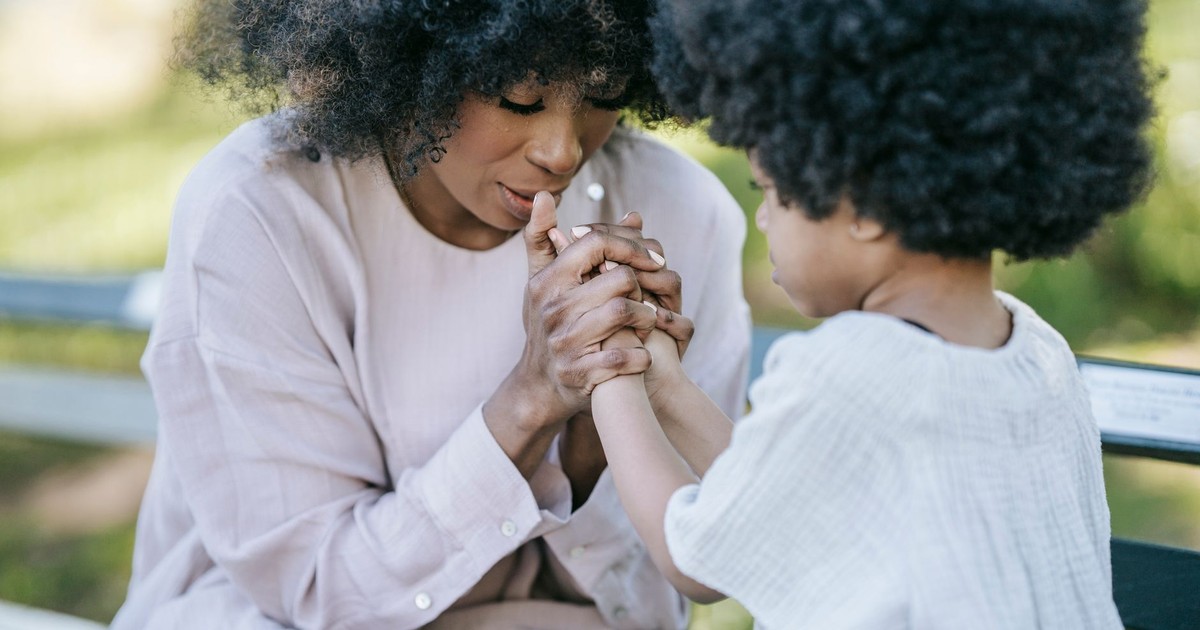 A heartwarming moment between a mother and daughter holding hands outdoors.