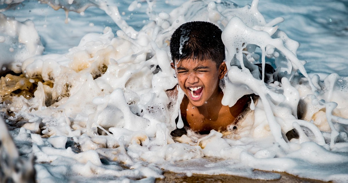 Joyful young boy enjoying splashing waves at the beach on a sunny day.