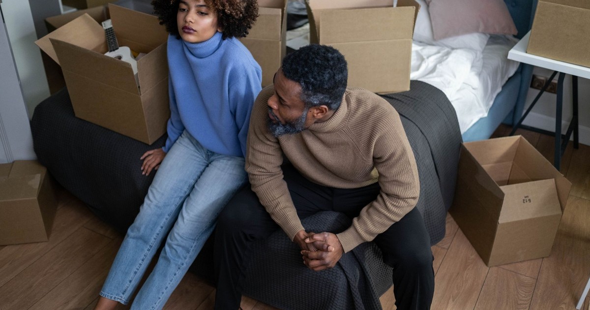 African American couple packing boxes in their bedroom, preparing to move.
