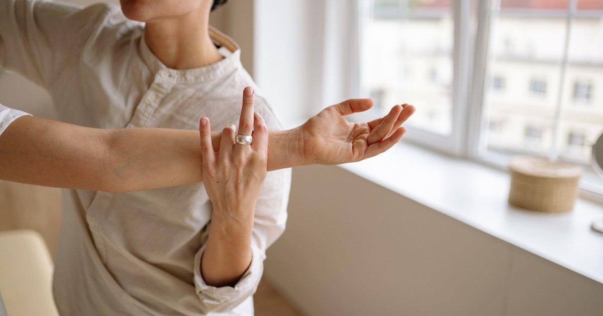 Physical therapist stretches a woman's arm in a sunny room.