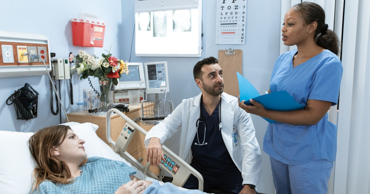 Doctors and nurse discussing patient's treatment in a hospital room.