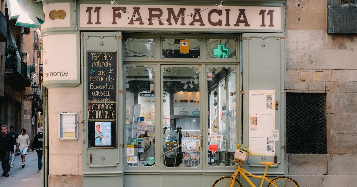 Rustic pharmacy storefront in Barcelona featuring a vintage bicycle and classic signage.