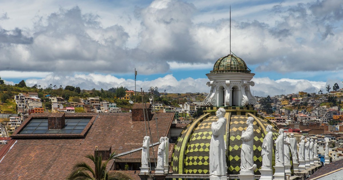 A beautiful architectural dome with statues viewed against an urban backdrop under a vibrant sky.