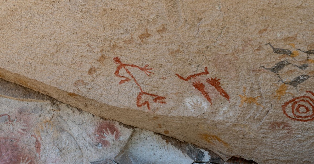 Ancient petroglyphs depicting abstract figures and symbols on a rock surface.