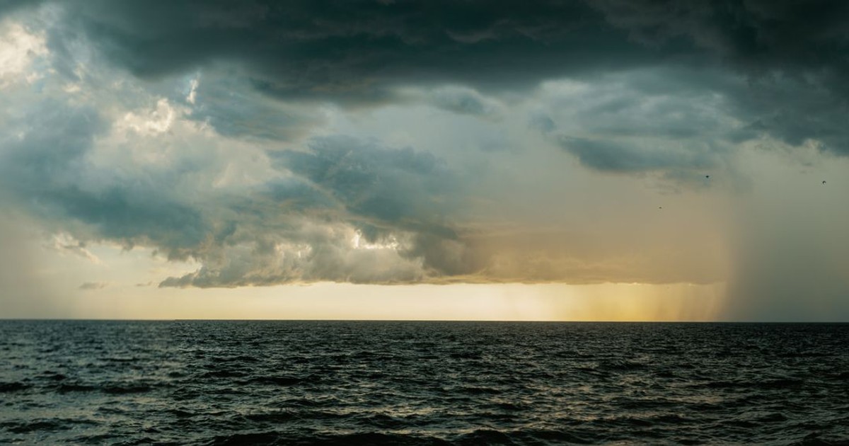A vast ocean under stormy skies with dramatic dark clouds and rainfall.