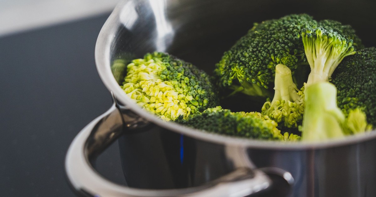 Close-up of fresh broccoli being cooked in a stainless steel pot, showcasing healthy eating.