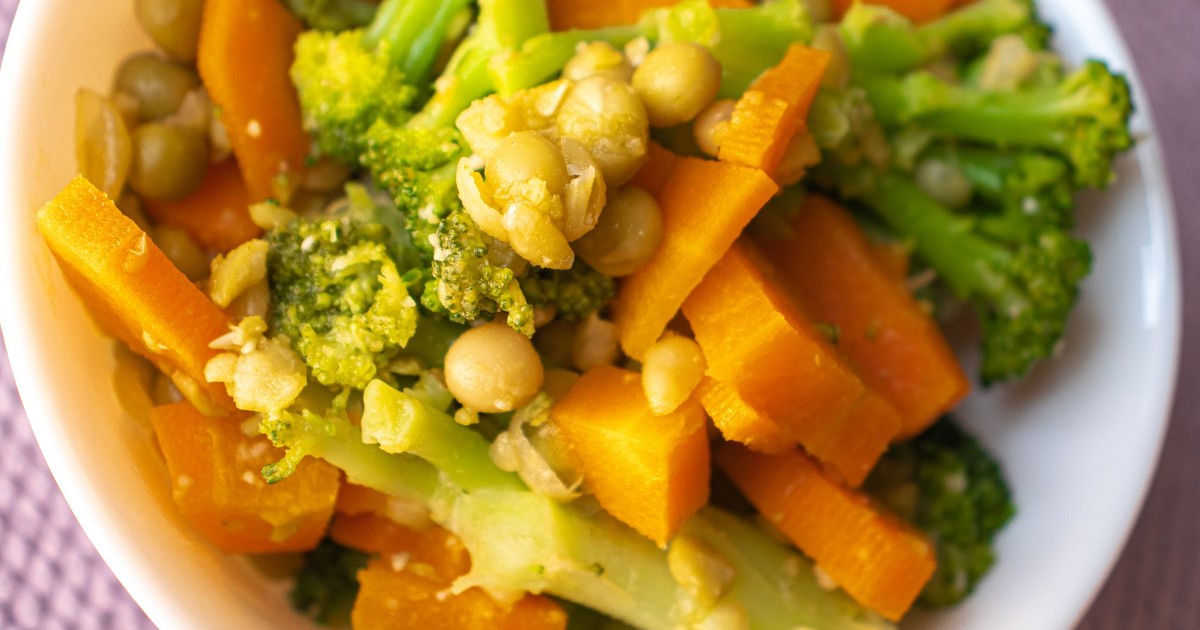 Colorful mix of steamed carrots, broccoli, and peas in a white bowl.