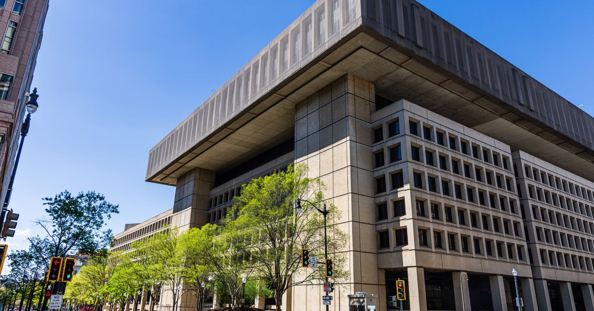Photo of a modernist government building with a distinct overhang, taken on a sunny day with clear blue skies.