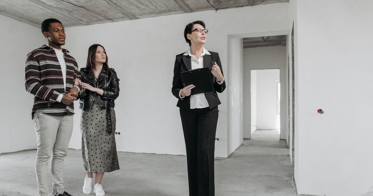 A real estate agent shows an unfinished apartment to prospective buyers.