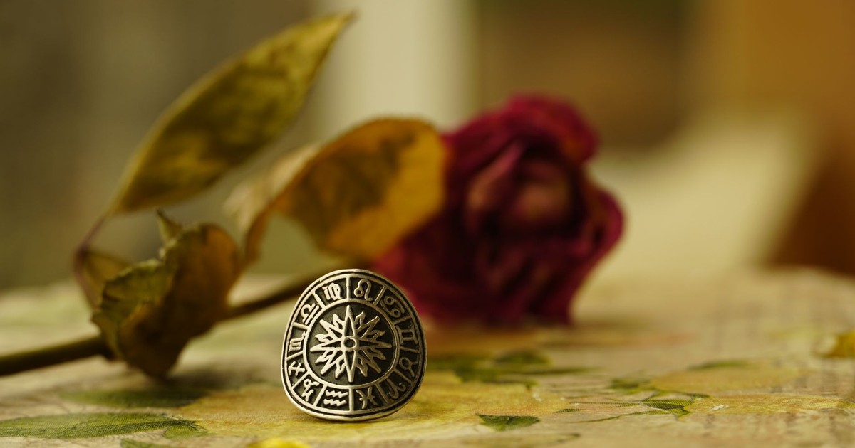 Close-up of a zodiac-themed ring with dried flowers in a warm, artistic setting.