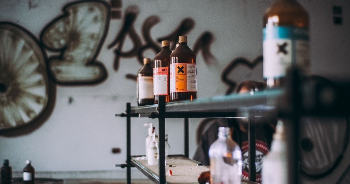 Discover an abandoned industrial room featuring shelves of toxic chemical bottles and graffiti walls.