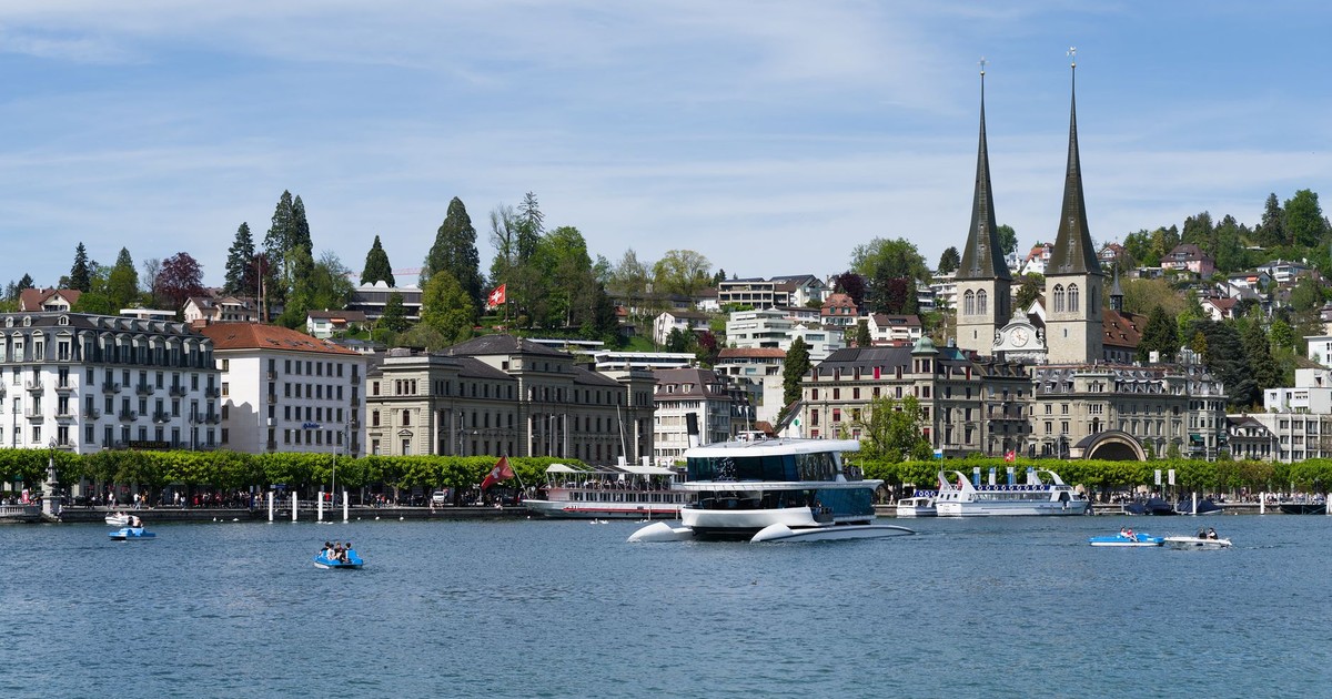 Beautiful view of Lake Lucerne with boats and iconic city skyline featuring spires and historic architecture.